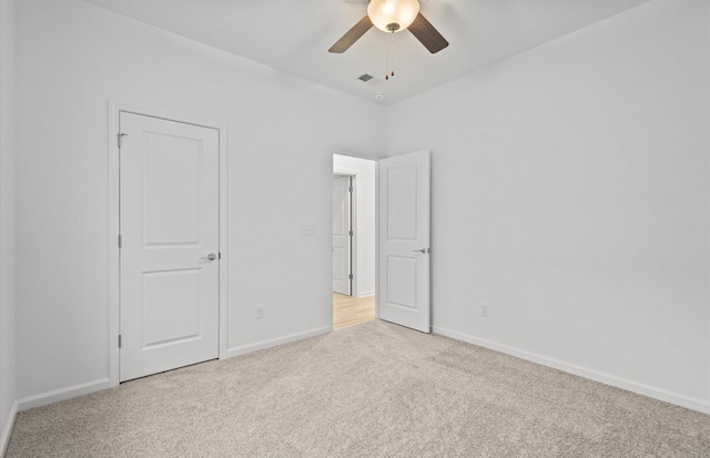 unfurnished bedroom featuring a ceiling fan, light colored carpet, and baseboards