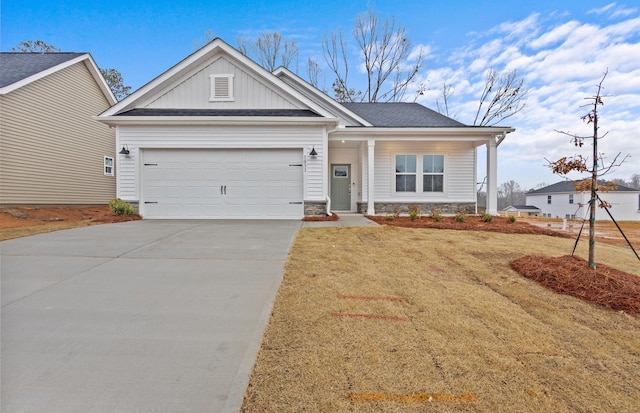 craftsman-style home with a garage, concrete driveway, stone siding, a front lawn, and board and batten siding