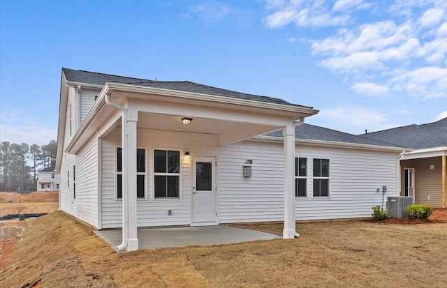 back of house featuring a yard, central AC, a patio, and roof with shingles