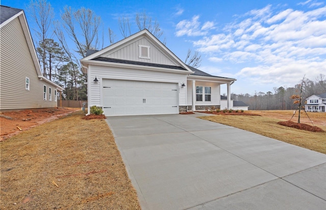 view of front of house featuring an attached garage, board and batten siding, a front yard, stone siding, and driveway