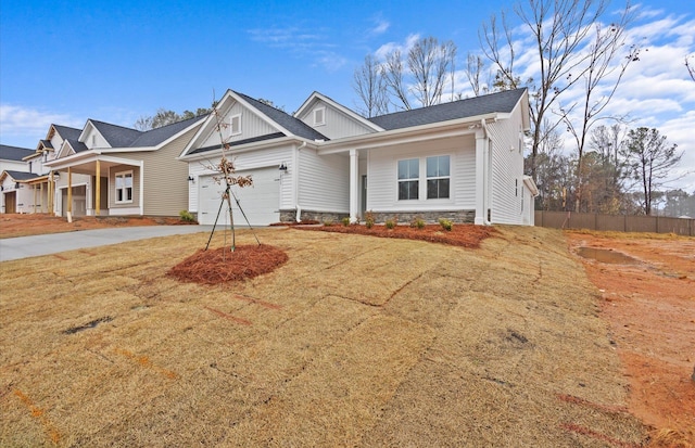 craftsman-style home with driveway, a garage, stone siding, fence, and a front lawn