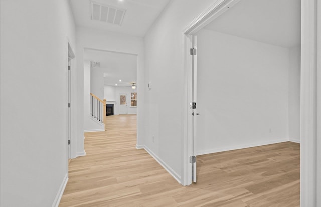 hallway featuring light wood-type flooring, visible vents, and baseboards