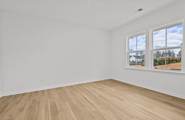 empty room with light wood-style floors, baseboards, and visible vents