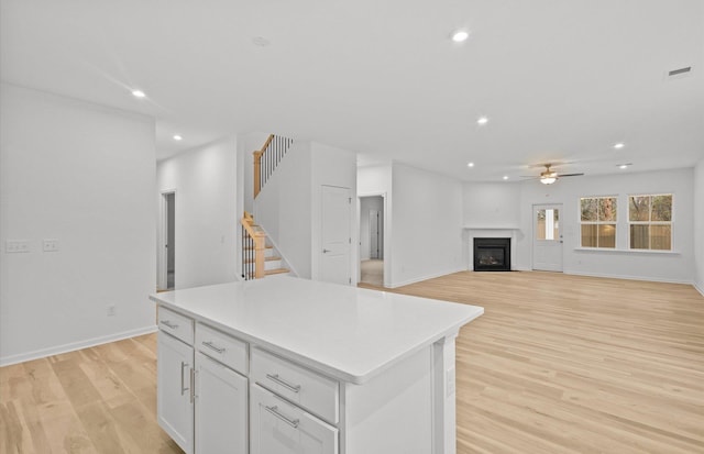 kitchen featuring white cabinets, open floor plan, light countertops, and a center island