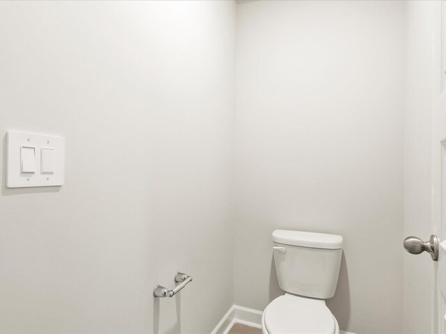 bathroom with baseboards and toilet