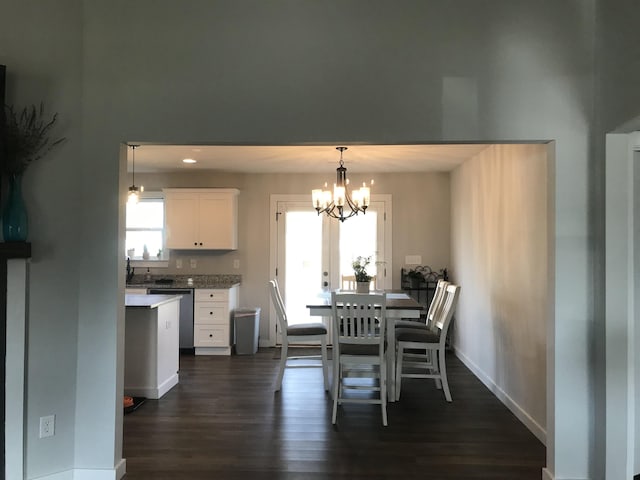 dining room with baseboards, dark wood-type flooring, an inviting chandelier, and a healthy amount of sunlight