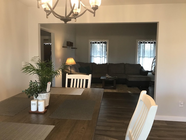 dining space featuring a chandelier, dark wood finished floors, and baseboards