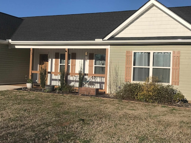 rear view of property featuring covered porch and a yard