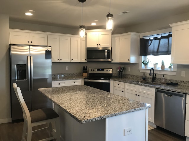 kitchen featuring appliances with stainless steel finishes, white cabinetry, a sink, and a kitchen island