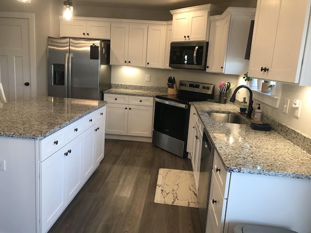 kitchen with appliances with stainless steel finishes, a center island, white cabinets, and a sink