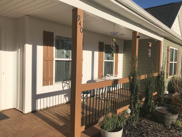 view of side of property featuring covered porch and roof with shingles