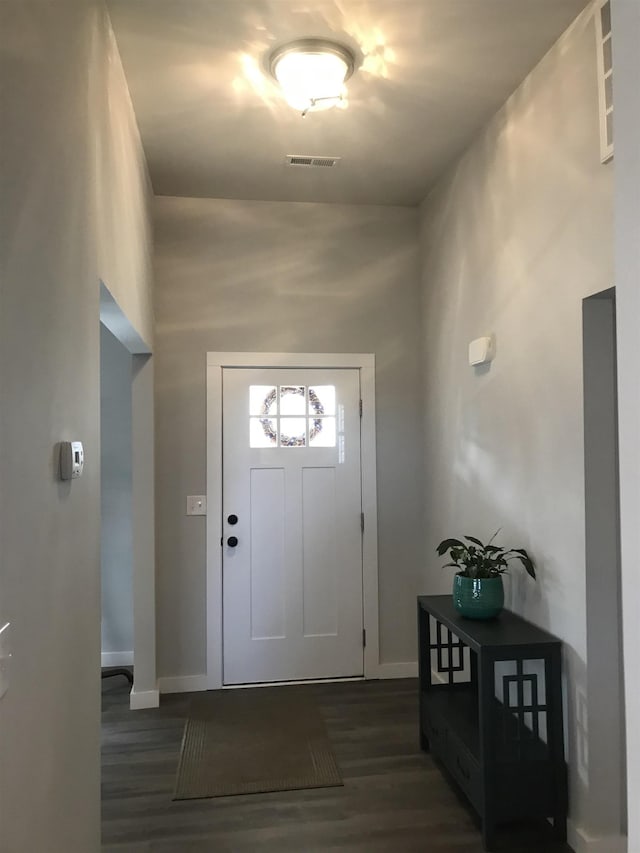 foyer entrance with dark wood-style flooring, visible vents, and baseboards