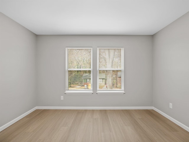 spare room featuring baseboards and light wood-style floors