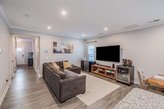 living area with baseboards, light wood-style flooring, visible vents, and crown molding