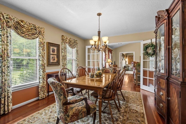 dining room featuring dark wood-style floors, a textured ceiling, a chandelier, and a wealth of natural light