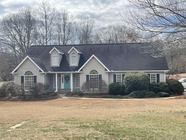 new england style home with a front lawn and roof with shingles