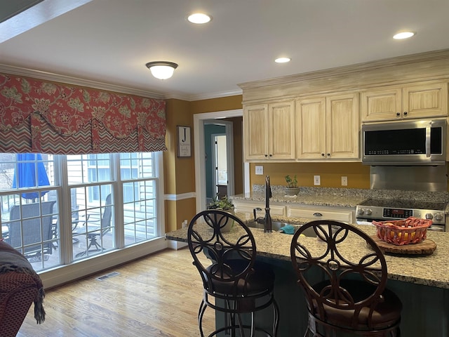 kitchen with ornamental molding, stainless steel appliances, light stone counters, and light wood-style floors