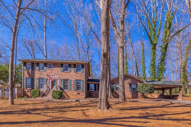 colonial inspired home featuring a carport, brick siding, and crawl space