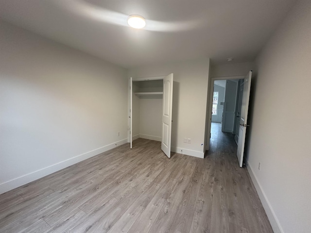 unfurnished bedroom featuring light wood-style floors, a closet, and baseboards