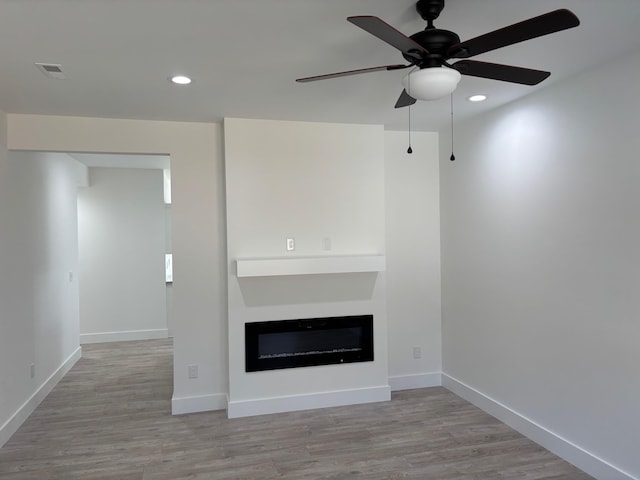 unfurnished living room with light wood-type flooring, recessed lighting, and a glass covered fireplace