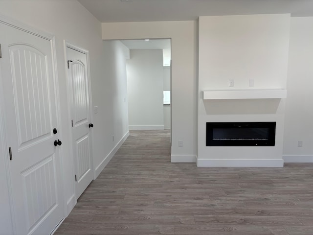 interior space with a fireplace, light wood-style flooring, and baseboards