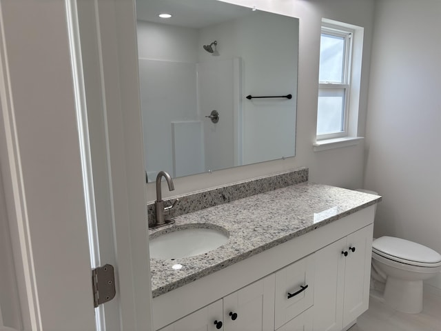 bathroom with toilet, walk in shower, and vanity