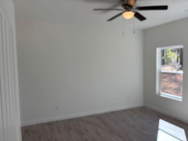 spare room featuring dark wood finished floors, baseboards, and ceiling fan