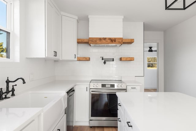 kitchen with a sink, white cabinetry, light countertops, appliances with stainless steel finishes, and custom range hood