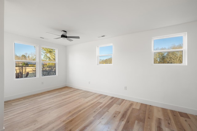 unfurnished room featuring a ceiling fan, visible vents, light wood-style flooring, and baseboards