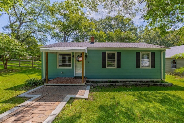 view of front of property with roof with shingles, a chimney, and a front yard