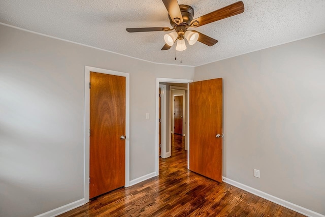 unfurnished bedroom with ceiling fan, a textured ceiling, baseboards, and dark wood-type flooring