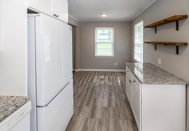 kitchen with white appliances, baseboards, light stone countertops, a textured ceiling, and white cabinetry