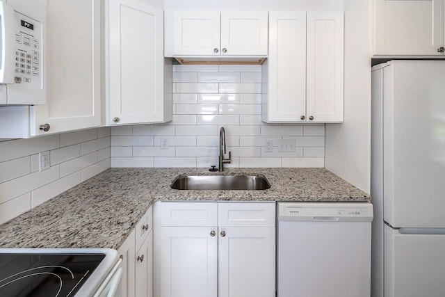 kitchen featuring light stone counters, decorative backsplash, white cabinets, a sink, and white appliances