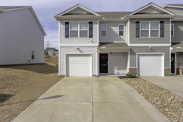 view of front of house with driveway, stone siding, and an attached garage