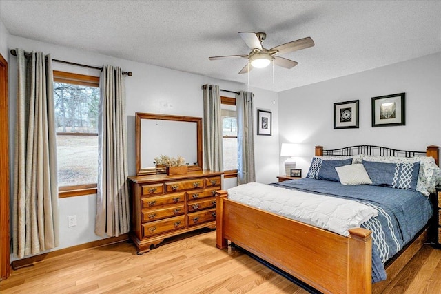 bedroom featuring a textured ceiling, light wood-type flooring, and a ceiling fan