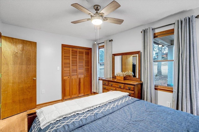 bedroom with a textured ceiling, wood finished floors, a ceiling fan, baseboards, and a closet