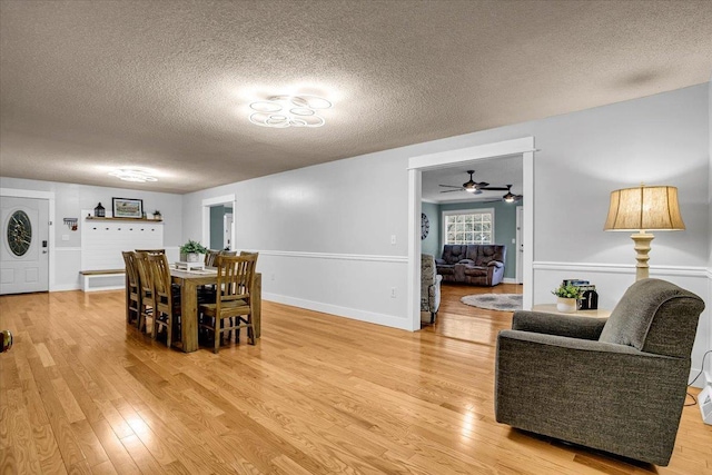 dining area featuring a textured ceiling, baseboards, and wood finished floors