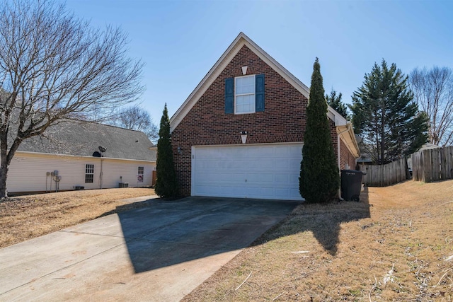 view of home's exterior featuring an attached garage, fence, concrete driveway, and brick siding