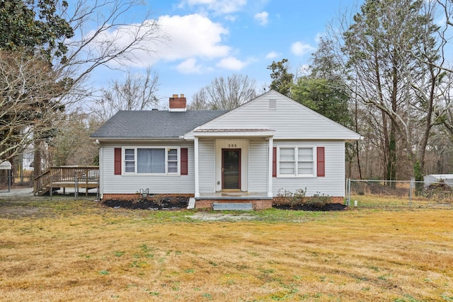 view of front of property with a wooden deck, a chimney, fence, and a front yard