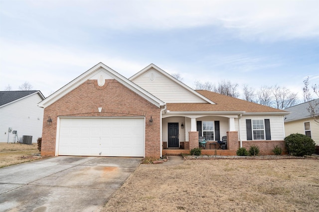 view of front facade with brick siding, central air condition unit, covered porch, an attached garage, and driveway