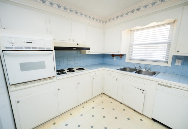 kitchen featuring white appliances, light countertops, under cabinet range hood, and white cabinetry