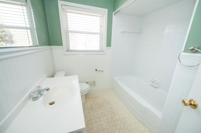 bathroom featuring visible vents, toilet, wainscoting, a sink, and tile patterned floors