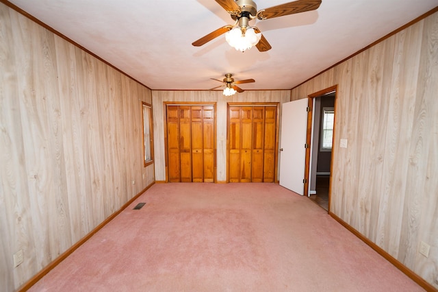 unfurnished room featuring ornamental molding, light colored carpet, visible vents, and wooden walls