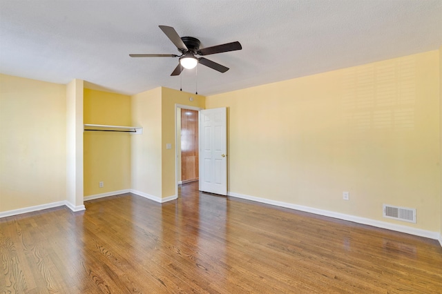 empty room with a ceiling fan, baseboards, visible vents, and wood finished floors