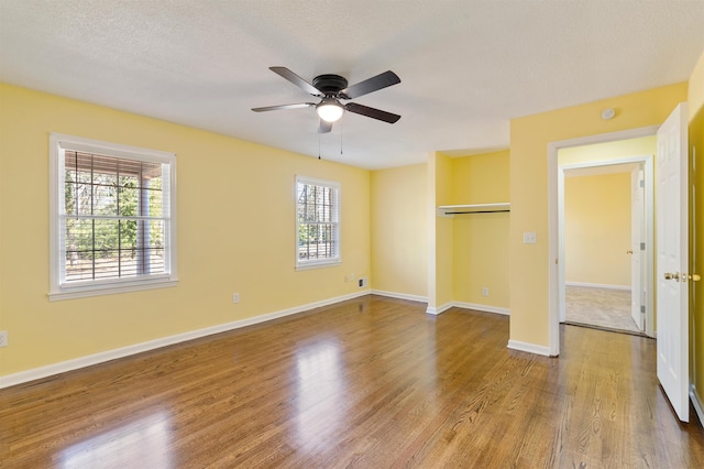 unfurnished bedroom featuring a textured ceiling, wood finished floors, a ceiling fan, and baseboards