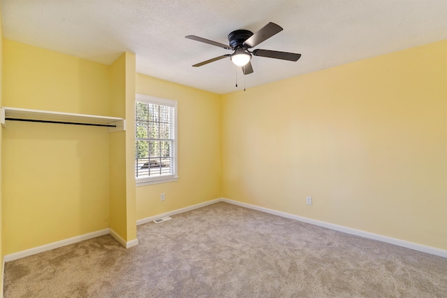 unfurnished bedroom featuring carpet, visible vents, a textured ceiling, and baseboards