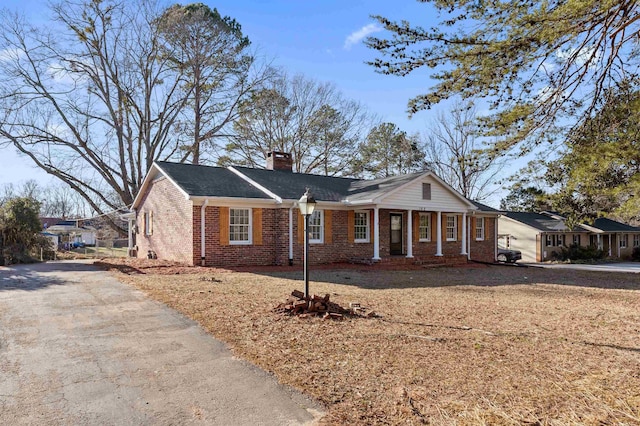 single story home featuring a chimney and brick siding