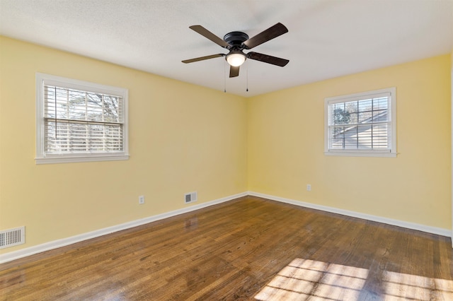 unfurnished room with a ceiling fan, baseboards, visible vents, and dark wood-style flooring