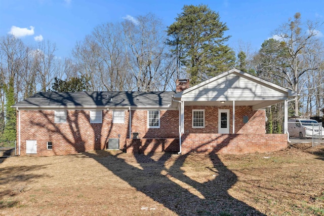 rear view of property with central AC unit, a chimney, crawl space, a yard, and brick siding