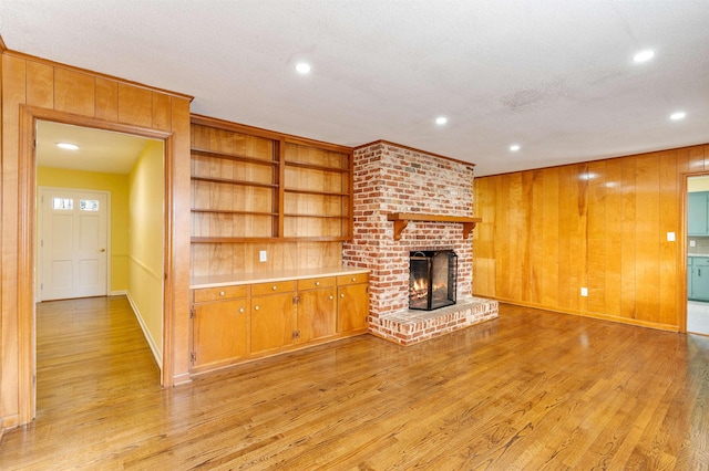 unfurnished living room with wood walls, light wood-style flooring, and a fireplace